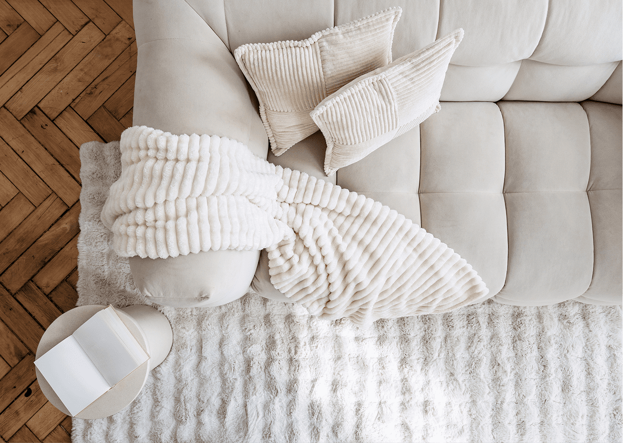 Cozy white sofa with pillows and throw